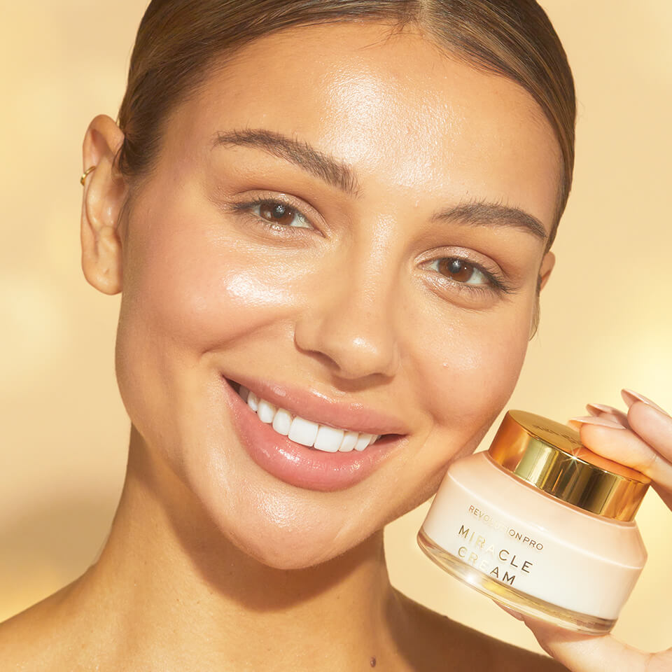 A close-up of a person smiling holding the Miracle Cream Bottle